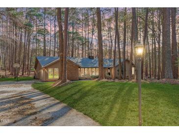 Charming single-story brick home with well-manicured lawn and mature trees, exuding curb appeal and natural beauty at 11808 Black Horse Run, Raleigh, NC 27613