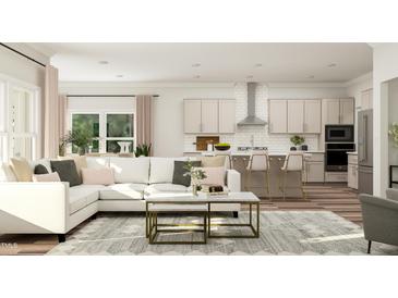 An open living room and kitchen area with a white sectional couch and kitchen island with seating for three at 1569 Goldfinch Perch Ln, Knightdale, NC 27545
