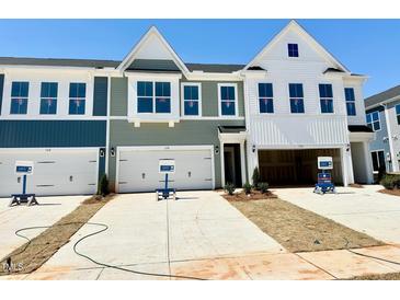 View of townhomes with varied exteriors and attached garages and driveways on a sunny day at 158 Nimble Way # 226, Clayton, NC 27520