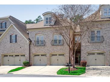 Elegant townhome featuring a brick facade, multiple garage bays, and Juliet balconies on the second floor at 162 Arabella Ct, Cary, NC 27518