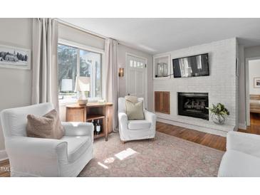 Comfortable living room with white armchairs, fireplace, and hardwood floors with decorative rug at 202 High St, Carrboro, NC 27510