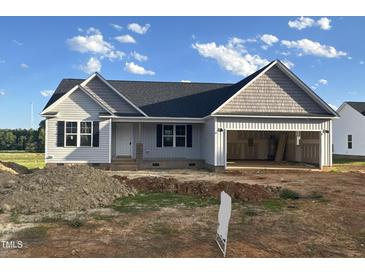Charming single-Gathering home featuring a spacious two-car garage and stylish gray siding, set under a bright blue sky at 207 N Movado Trl, Kenly, NC 27542
