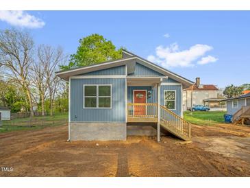 Charming blue home with a cozy front porch and freshly landscaped yard, providing curb appeal at 230 N Melville St, Graham, NC 27253