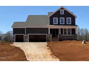 New two-story home featuring a three-car garage and a charming front porch with stone accents at 4893 Grosbeak Ct, Mebane, NC 27302