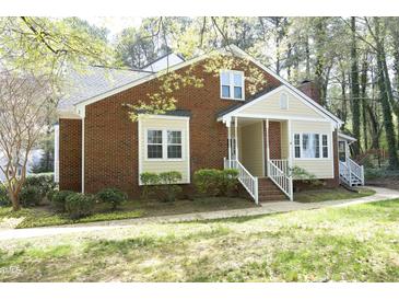 Charming brick home with cream trim, a cozy front porch, and manicured front lawn at 8310 Wycombe Ln, Raleigh, NC 27615