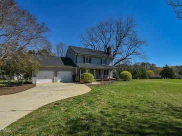 Charming two-story home with a two-car garage, large lawn, and mature landscaping on a sunny day at 10317 Lake Wheeler Rd, Fuquay Varina, NC 27526