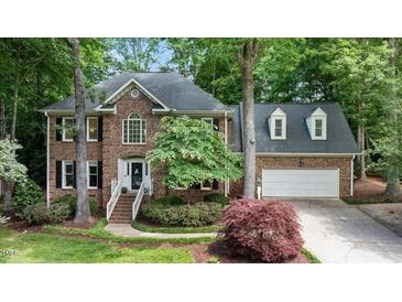Charming brick home with a two-car garage, manicured lawn, and mature trees at 306 Lochside Dr, Cary, NC 27518