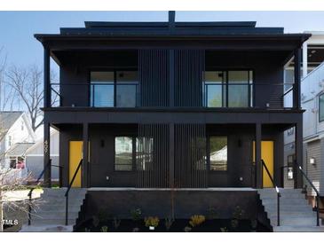 Modern black townhouse with two stories, balconies, black railings, and bright yellow doors at 409 Alston St # 101, Raleigh, NC 27601