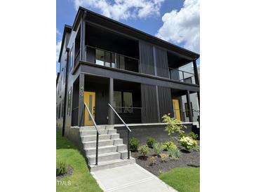 Modern two-story home featuring a striking dark exterior and a vibrant yellow front door at 409 Alston St # 101, Raleigh, NC 27601