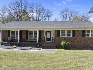 Charming brick home with a welcoming front porch and landscaped yard, perfect for enjoying the outdoors at 5705 Dean Ave, Raleigh, NC 27616