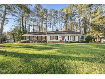 Charming ranch-style home with brick and siding exterior, red front door, and a lush green lawn at 11801 Strickland Rd, Raleigh, NC 27613