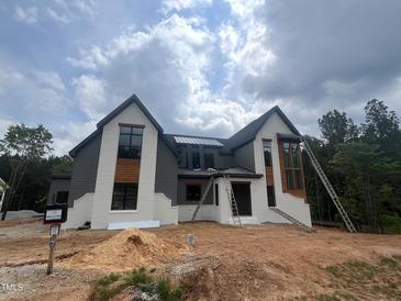 Two-story home with white brick, gray siding and a black roof against a cloudy sky at 170 Cherry Bark Dr, Youngsville, NC 27596