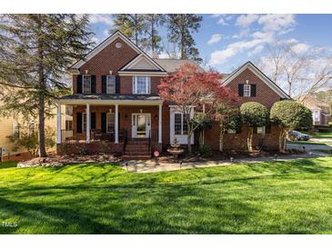 Beautiful two-story brick home with a manicured lawn, inviting front porch, and mature landscaping at 2900 London Bell Dr, Raleigh, NC 27614