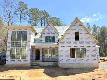 New construction shows the exterior of a beautiful two-story home with large windows and natural surroundings at 2957 Wexford Pond Way, Wake Forest, NC 27587