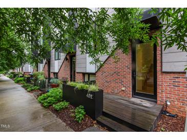 Modern townhome featuring brick and steel exterior with wood porch and landscaped planter at 402 Chavis Way, Raleigh, NC 27601