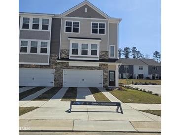 New townhome with a two-car garage, stone accents, and manicured lawn at 5320 River Reach Dr, Raleigh, NC 27616