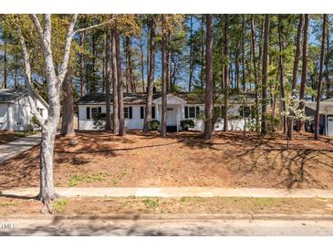 Charming white brick home with black shutters surrounded by mature trees at 5812 Timber Ridge Dr, Raleigh, NC 27609