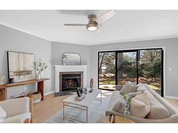 Bright living room featuring a fireplace, stylish decor, and sliding glass doors to the outside at 7706 Falcon Rest Cir, Raleigh, NC 27615