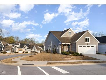 Charming gray home featuring an attached two-car garage and manicured lawn on a tree-lined street at 101 Maroon Ct, Raleigh, NC 27610