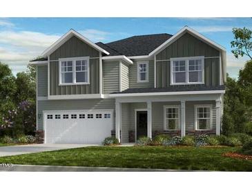 Charming two-story home with a white garage door and lush green landscaping, creating an inviting curb appeal at 1129 Sun Springs Rd, Wake Forest, NC 27587