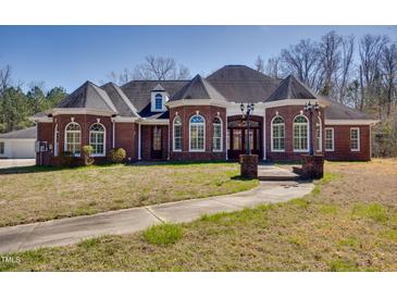 Elegant brick home featuring arched windows, dormers, and a landscaped walkway leading to the entrance at 119 Cardinal Crest Ct, Pittsboro, NC 27312