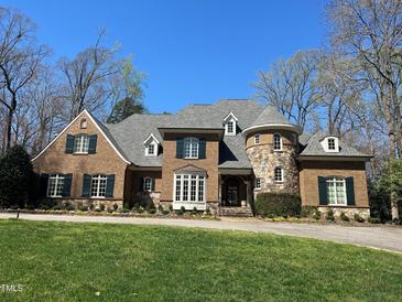 Beautiful brick home featuring manicured lawn, dormer windows, a stone turret, and dark green shutters at 2207 Oxford Rd, Raleigh, NC 27608