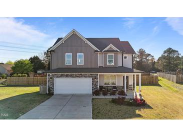 Charming two-story home with stone accents, a well-manicured lawn, and an attached two-car garage at 35 Wolf Ridge Ct, Willow Springs, NC 27592