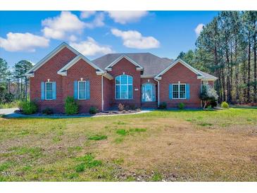 Charming red brick home with blue shutters and well-manicured front lawn under a bright sky at 7687 Mattie Rd, Rocky Mount, NC 27803