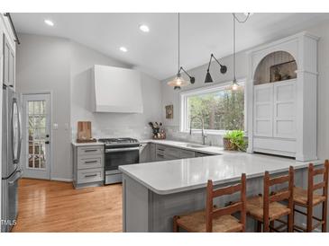 Bright kitchen boasts gray cabinetry, hardwood floors, and large sink with a view of the outdoors at 8504 Old Nc 86, Chapel Hill, NC 27516