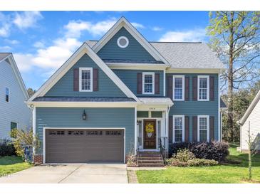 Charming two-story home with blue siding, brown shutters, attached garage, and a well-manicured front yard at 8704 Paddle Wheel Dr, Raleigh, NC 27615