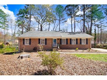 Charming brick ranch-style home with mature trees and established landscaping creating a welcoming curb appeal at 104 Amberhill Ct, Garner, NC 27529