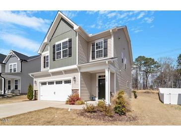 Two-story home featuring a two-car garage and a covered front porch and professional landscaping at 117 Highland Forest Dr, Fuquay Varina, NC 27526