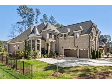 Stunning brick home with a three car garage, manicured lawn, and turret style architectural detail at 119 November Dr, Durham, NC 27712