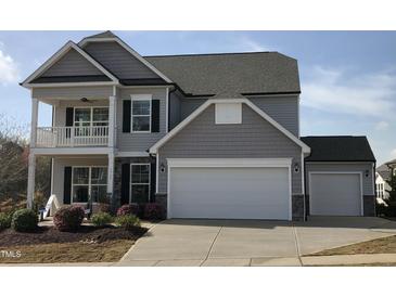 Two-story home featuring an attached garage, covered porch, and manicured landscaping at 1515 Willbrook Dr, Fuquay Varina, NC 27526