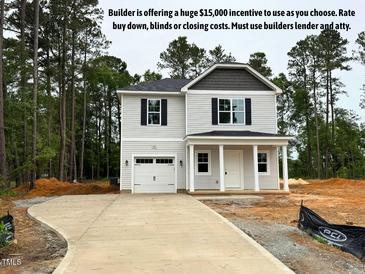 Charming two-story home featuring a light exterior, attached garage, and inviting front porch with stately columns at 187 Regis Ln # 10, Coats, NC 27521