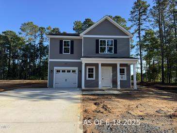 Charming two-story home featuring gray siding, a welcoming front porch with columns, and an attached one-car garage at 205 Regis Ln # 11, Coats, NC 27521