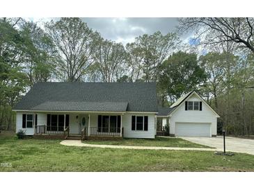 Charming home featuring a covered porch, attached garage, and mature trees, offering classic curb appeal at 2820 Mattlyn Ct, Raleigh, NC 27613
