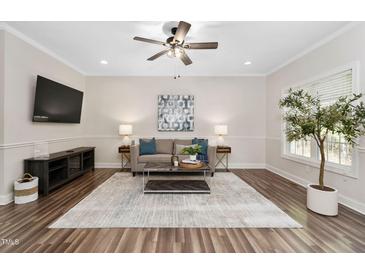 Bright living room featuring hardwood floors, a ceiling fan, neutral walls, and elegant furnishings at 50 Yelverton Ct, Holly Springs, NC 27540