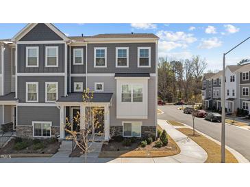 Gray townhome with stone accents, manicured landscaping, a private entrance, and visible street parking at 5200 Invention Way, Raleigh, NC 27616