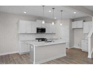 Bright kitchen with stainless steel appliances, white cabinetry, and a kitchen island at 104 Fairwinds Dr, Lillington, NC 27546