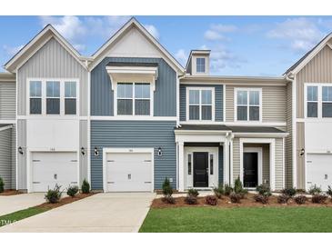 Charming two-story townhome featuring a one car garage, well-maintained lawn, and neutral color siding at 104 Ripple Way # 318, Clayton, NC 27520
