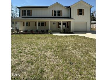 Charming two-story home with a welcoming front porch, natural wood shutters, and landscaped yard at 6932 Buckhorn Duncan Rd, Holly Springs, NC 27540