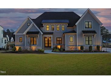 Stunning two-story home with craftsman style architecture and a manicured front lawn at twilight at 8005 Woodcross Way, Wake Forest, NC 27587