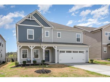 Charming two-story home featuring a covered front porch, attached two-car garage, and manicured landscaping at 1040 Lippincott Rd, Durham, NC 27703