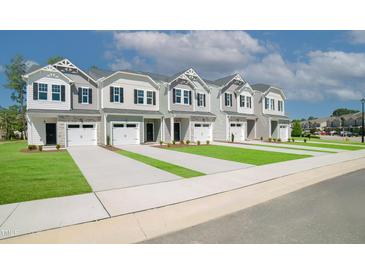 New construction townhomes featuring attached garages, neutral siding, and well-manicured lawns at 132 Rolesville Ridge Dr, Rolesville, NC 27571