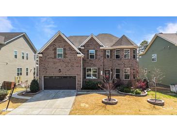 Beautiful brick two-story home with manicured landscaping and a two-car garage on a sunny day at 1624 Pantego Trl, Cary, NC 27519