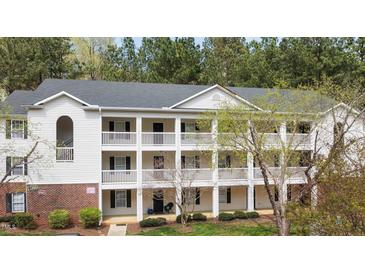 Three-story condo building with white siding, black shutters and balconies surrounded by lush trees at 2800 Trailwood Pines Ln # 301, Raleigh, NC 27603