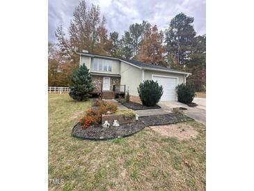Charming home featuring stone accents, a well-manicured lawn, and a convenient attached two-car garage at 306 Smoketree Way, Louisburg, NC 27549