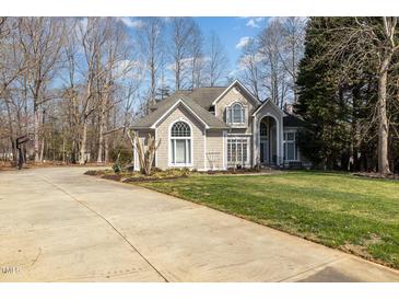 Charming home features a well-manicured lawn, complemented by a long driveway, and mature trees at 316 Pebble Beach Dr, Mebane, NC 27302