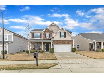 Inviting two-story home featuring a stone facade, attached garage, and well-manicured lawn at 3925 Massey Pointe Ct, Raleigh, NC 27616